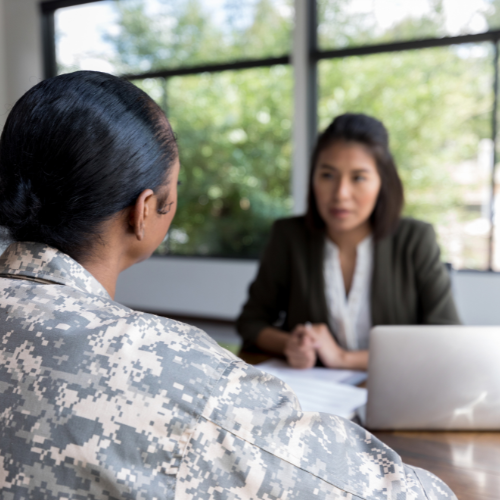 A military service member in camouflage attire in a consultation with a civilian partner at AboutFace-USA®